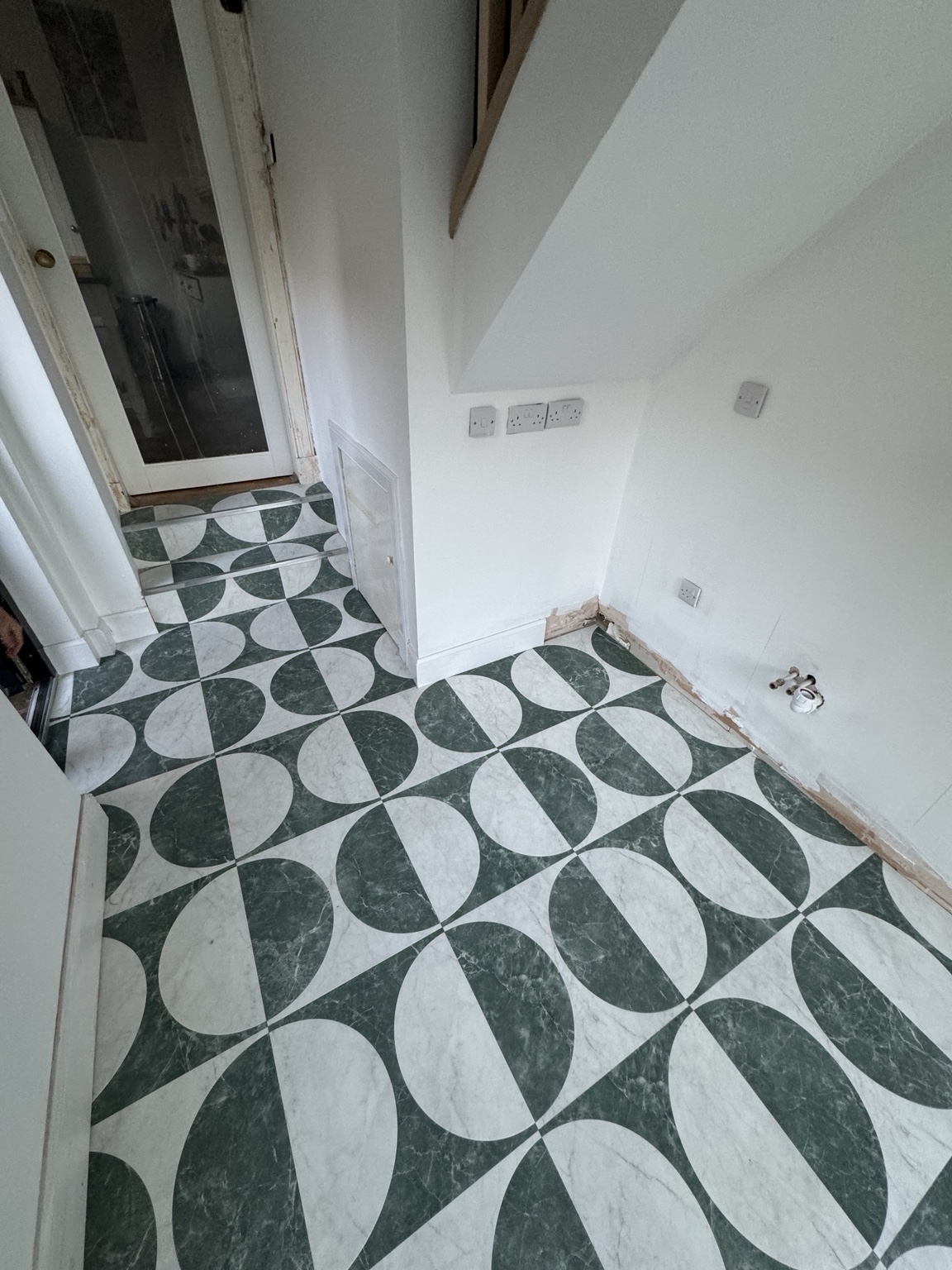 Green and white geometric flooring fitted through a hallway and steps