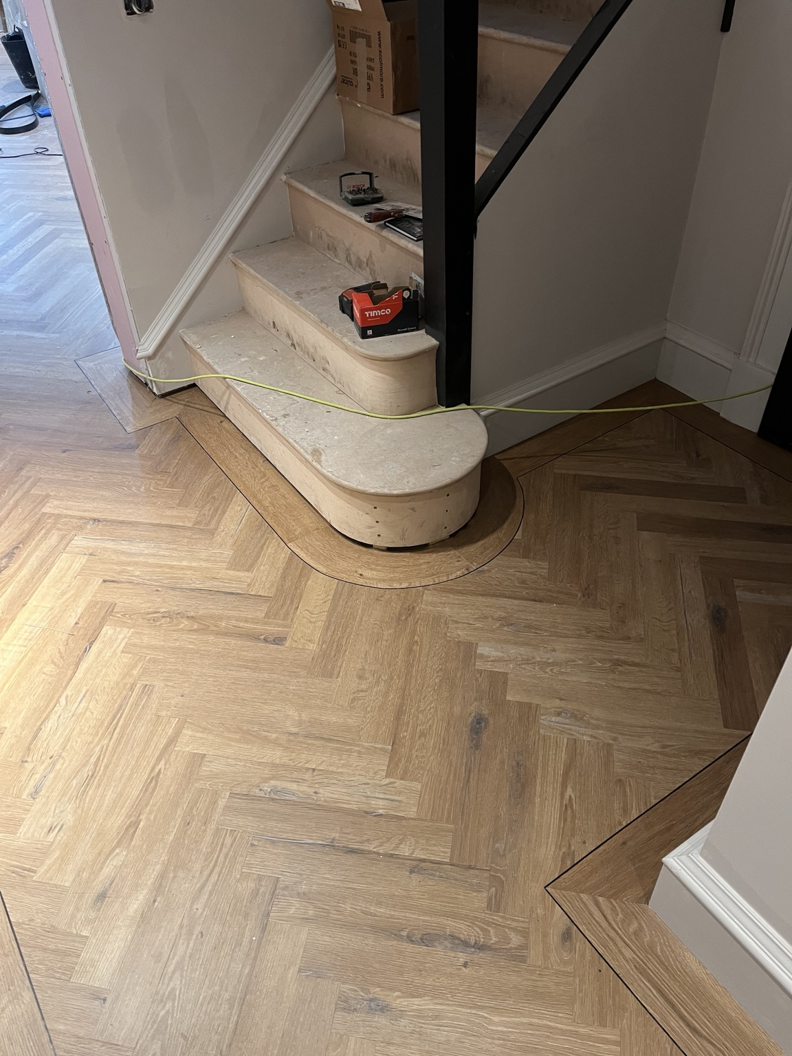 Herringbone LVT fitted around a curved staircase with a feature border