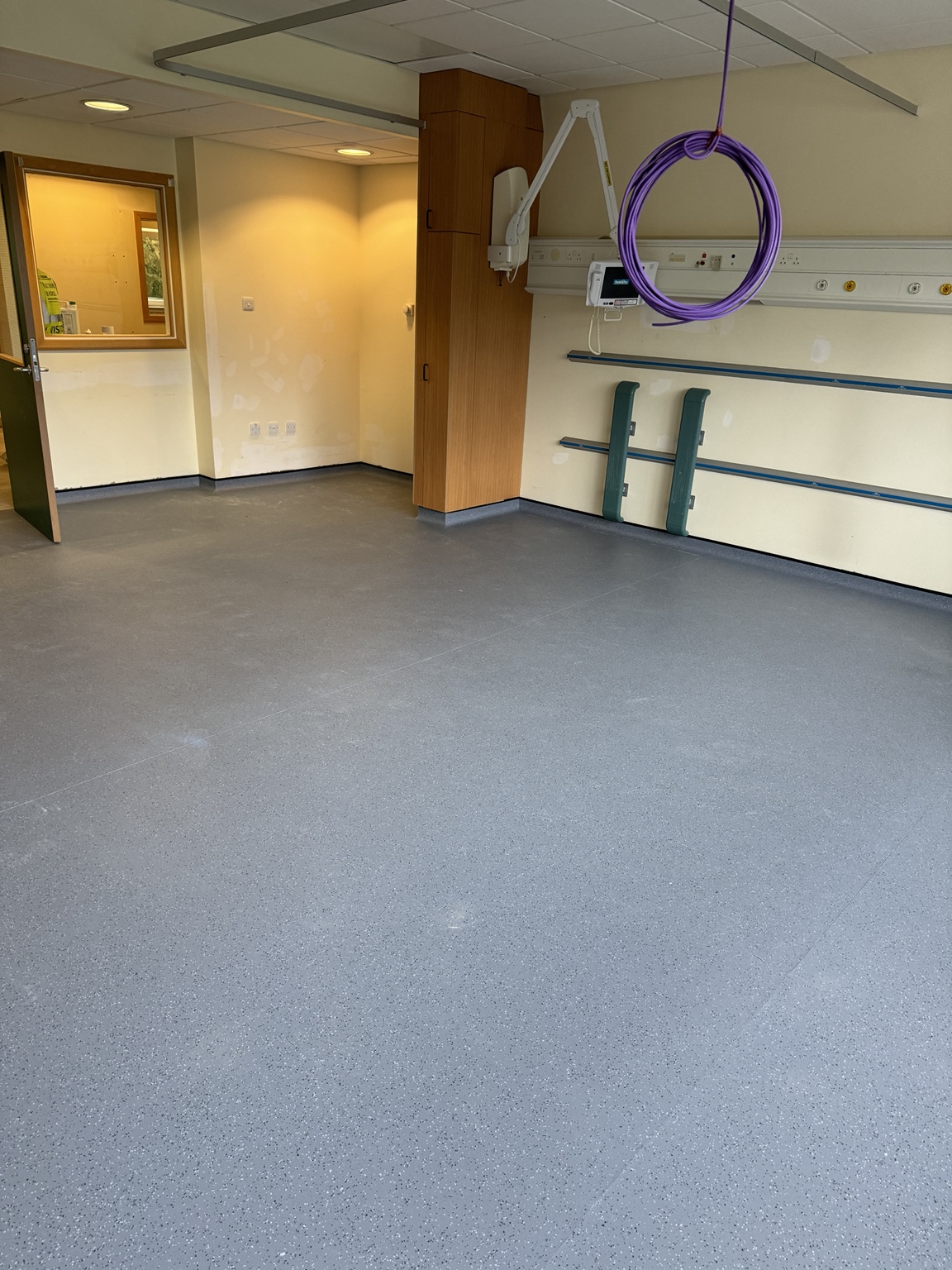Detailed cap-and-cove safety flooring finish around hospital room walls and joinery