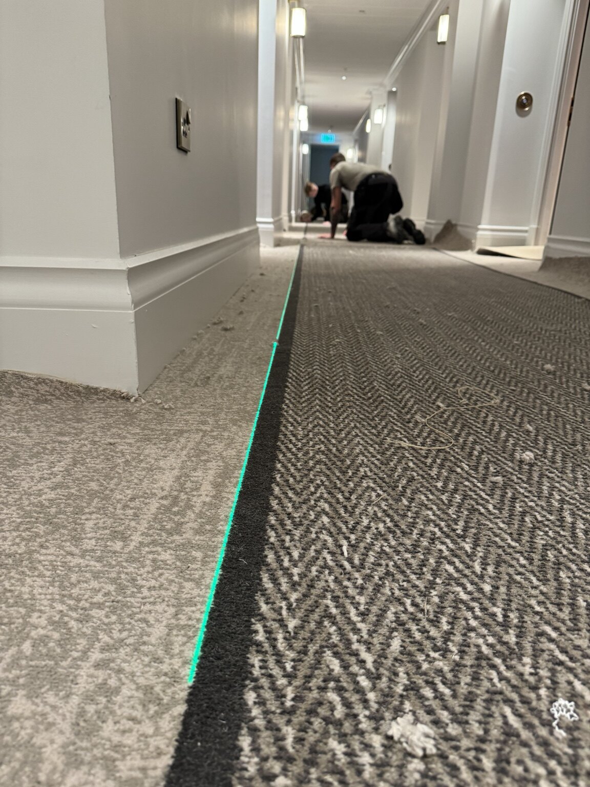 Border carpet being aligned during installation in a hotel hallway